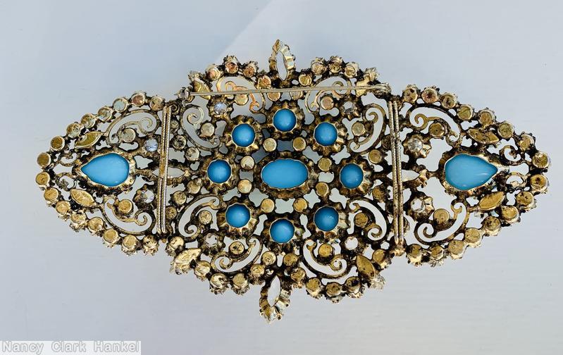 Schreiner diamond shaped radial scrollwork buckle bordered small invert stone oval cab center 8 surrounding round cab 2 large teardrop at end opaque baby blue round cab crystal inverted goldtone jewelry