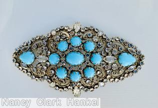 Schreiner diamond shaped radial scrollwork buckle bordered small invert stone oval cab center 8 surrounding round cab 2 large teardrop at end opaque baby blue round cab crystal inverted goldtone jewelry