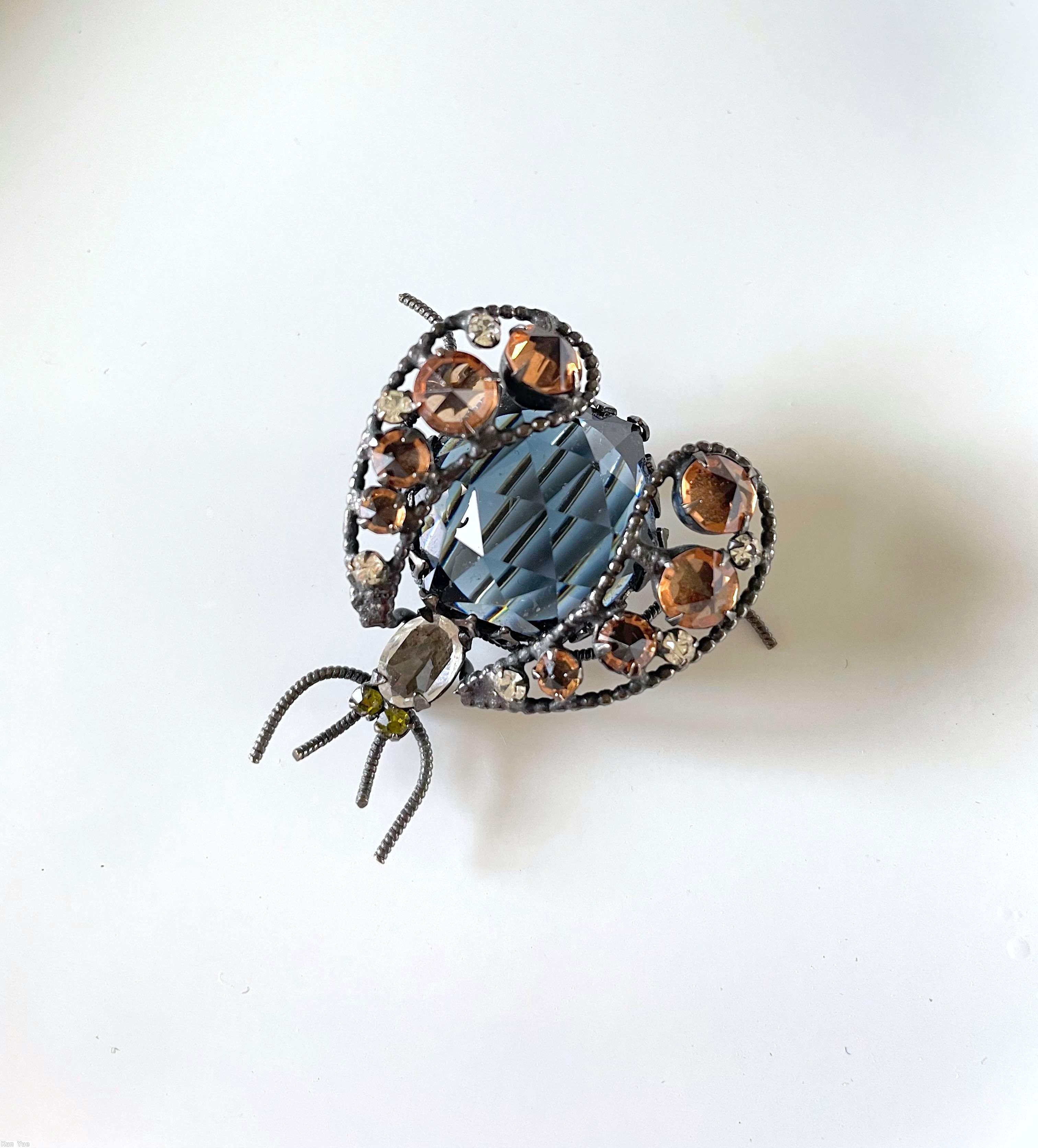 Schreiner bug 2 wing 4 whisker large round stone body 2 curly wire leg each wing 7 varied size stone 2 small chaton eye small oval stone head rose cut smoky blue large round stone topaz inverted faceted chaton peridot eye small chaton silvertone jewelry