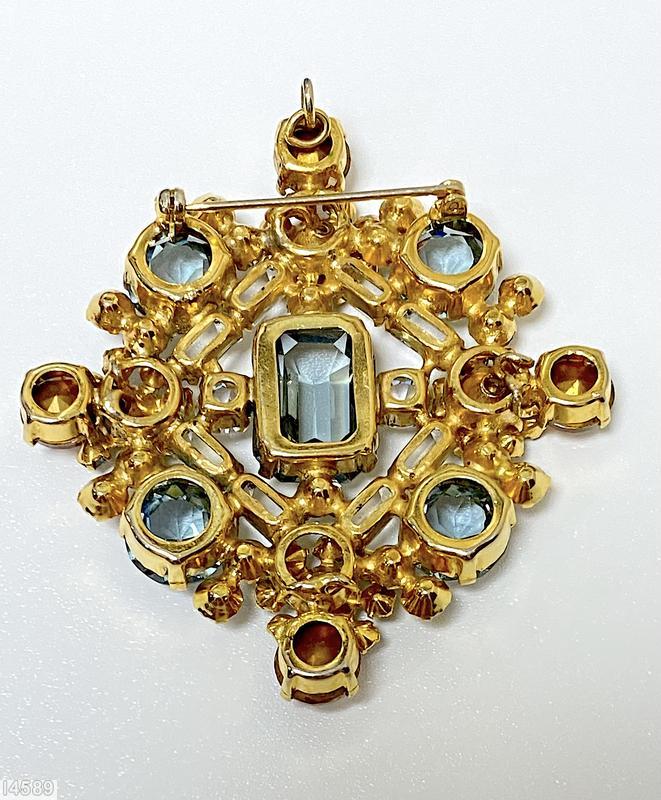 Schreiner diamond shaped radial pin elongated hexagon center stone 4 large round cab 4 flower head of 6 chatons surrounding 1 chaton 8 small baguette 4 small round cab clear champagne small baguette smoky blue large faceted chaton blue small inverted small inverted crystal faceted round topaz goldtone jewelry