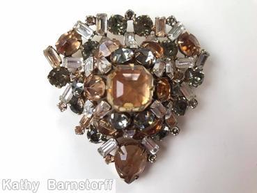 Schreiner domed triangle shaped pin large square stone center 1 large teardrop small baguette 4 surrounding small baguette 2 surrounding oval stone 4 surrounding chaton clear brown faceted teardrop crystal smoke goldtone jewelry