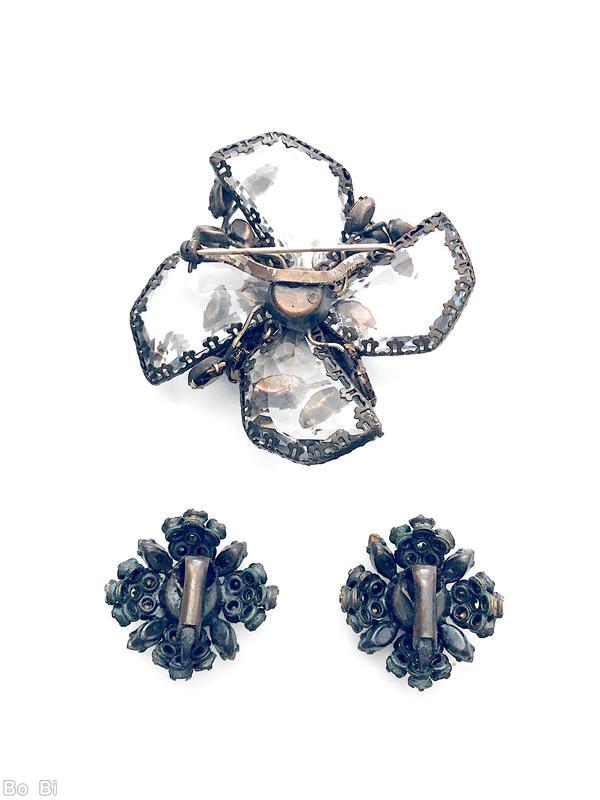 Schreiner radial 2 level pin bottom 4 large surrounding swirling faceted semicircle crystal with irregular edge top chaton center 4 surrounding flower head 4 surrounding small navette 4 small bush branch of small navette large faceted crystal brown metalic chaton gold flussed brown small navette peridot small chaton gunmetal coating on copper back jewelry