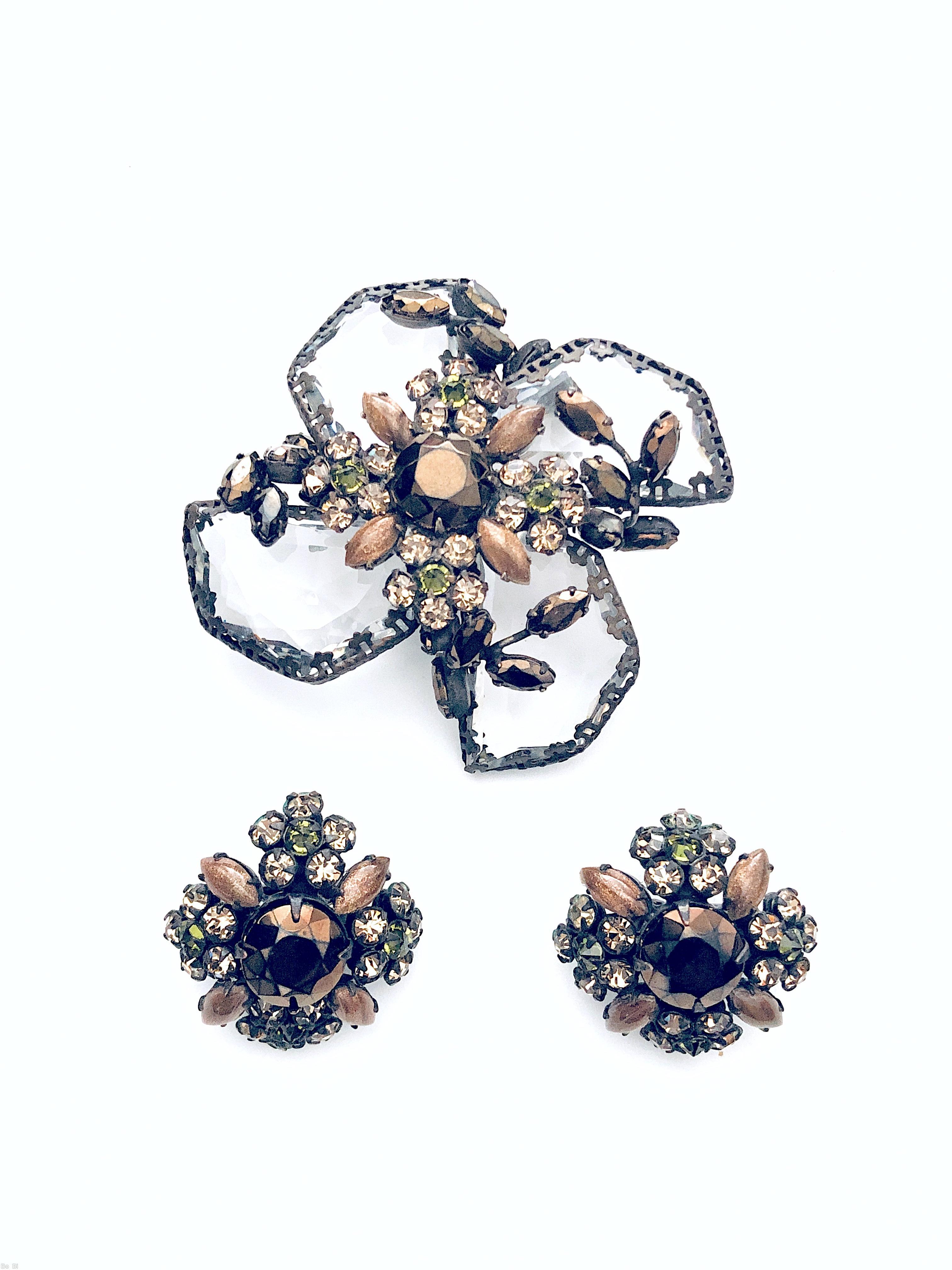 Schreiner radial 2 level pin bottom 4 large surrounding swirling faceted semicircle crystal with irregular edge top chaton center 4 surrounding flower head 4 surrounding small navette 4 small bush branch of small navette large faceted crystal brown metalic chaton gold flussed brown small navette peridot small chaton gunmetal coating on copper back jewelry