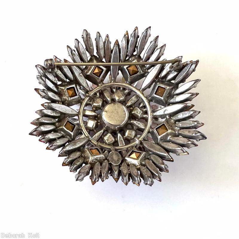 Schreiner round shaped flat top radial navette pin large chaton center 6 small square surrounding stone 6 navette surrounding stone 8 large square stone purple faceted large round stone center peach small square stone pink navette clear ice pink square stone lavender navette silvertone jewelry