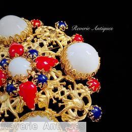 Schreiner square radial pin metal deco 4 large round stone at corner round stone center 4 surrounding heardrop 4 surrounding small chaton patriot milk white large round cab red opaque teardrop blue opaque teardrop goldtone jewelry