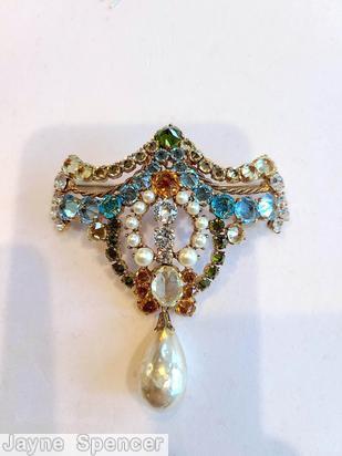 Schreiner top down dangling pin top part bilateral symmetry arc of varied size inverted stone double twisted metal wire 3 stone in a row center one large oval stone large dangling teardrop peridot inverted stone faux pearl large teadrop baroque faux pearl clear champagne faceted large oval stone aqua inverted stone crystal goldtone jewelry