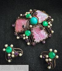 Schreiner triangle domed radial pin 3 surrounding large molded marbled tapezoid stone scrollwork 3 chatong 1 large round cab center 3 small surrounding pearl 18 small seeds pearl 18 small chaton pink marbled molded tapezoid stone peking glass round cab purple small chaton goldtone jewelry